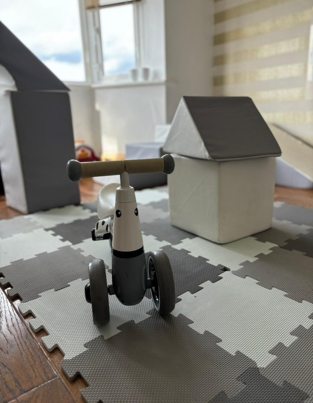 Ride-on trike on grey and white soft play mats with soft house block