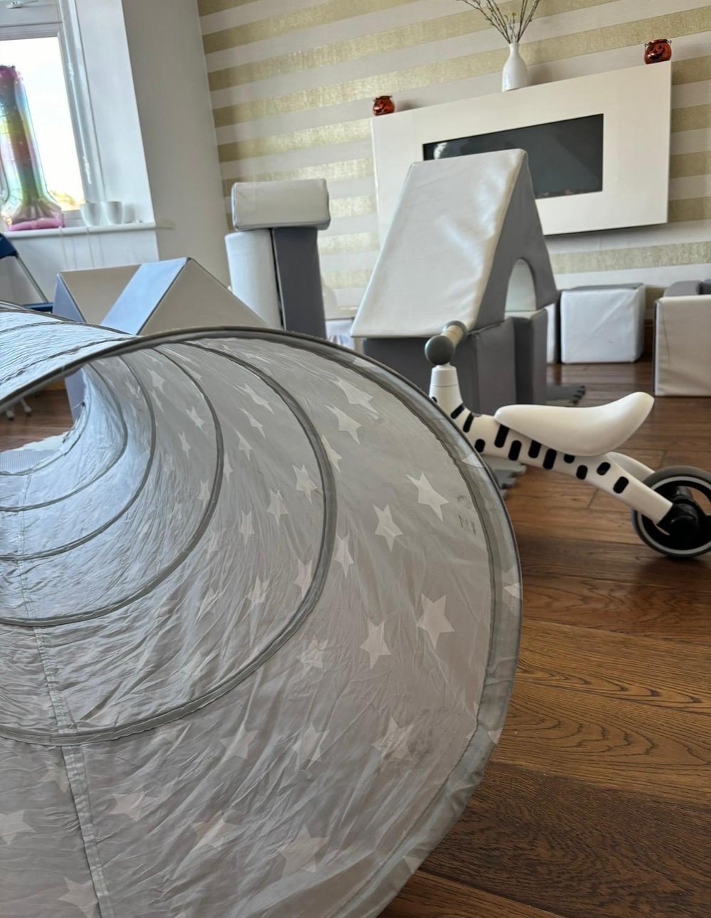 Close-up of star-print soft play tunnel with grey and white blocks in the background