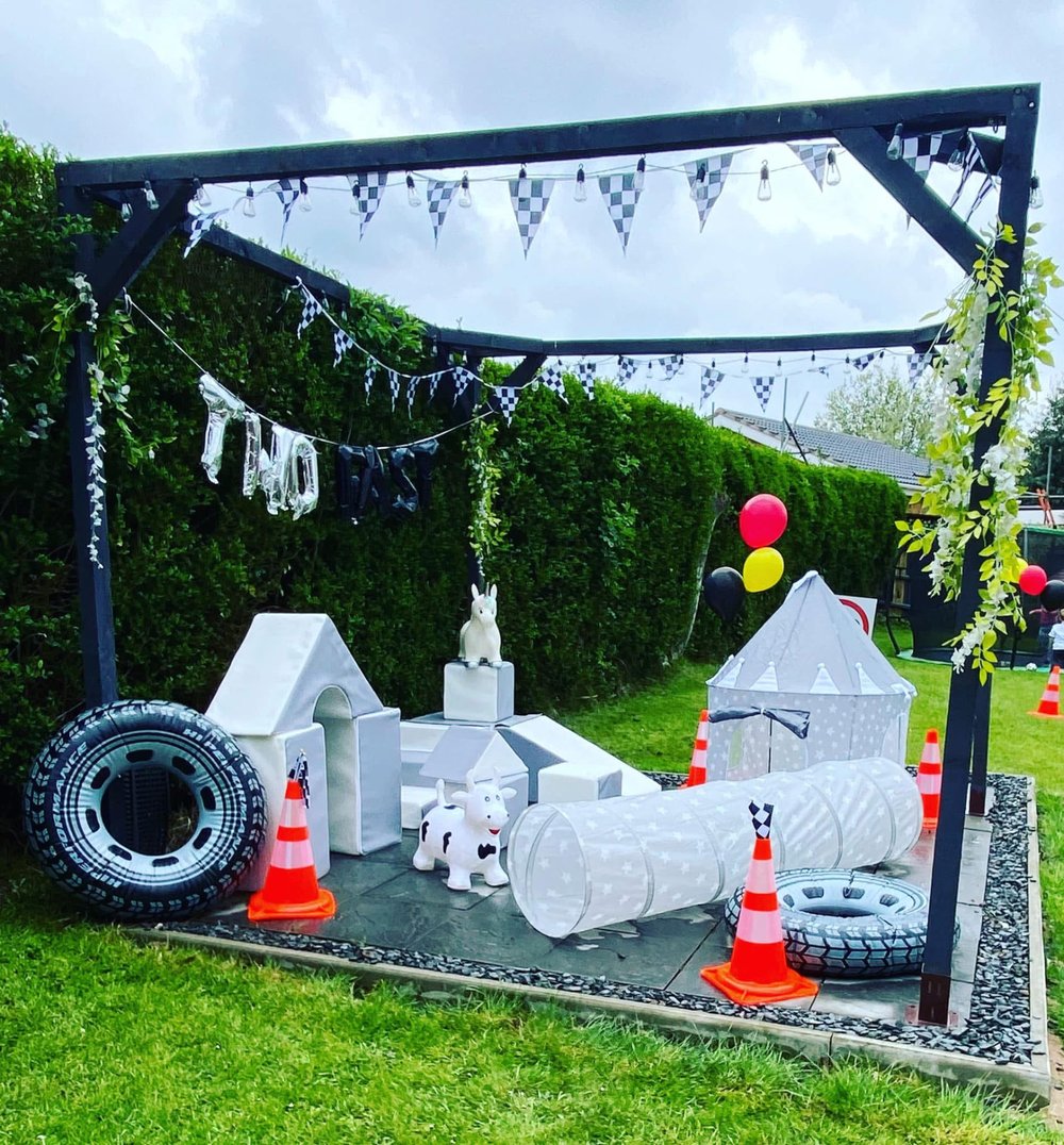 Outdoor race-car themed second birthday soft play setup under a pergola