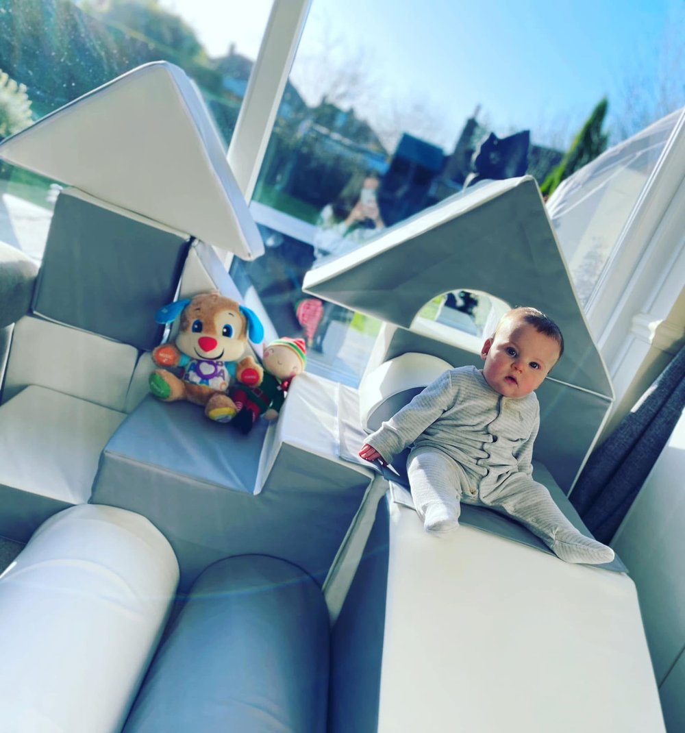 Baby playing on a soft play step-and-slide at home