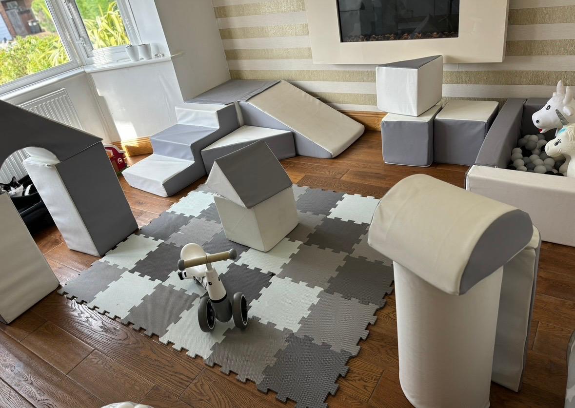 Living room soft play setup with step and slide, soft blocks, ball pit and ride-on unicorn