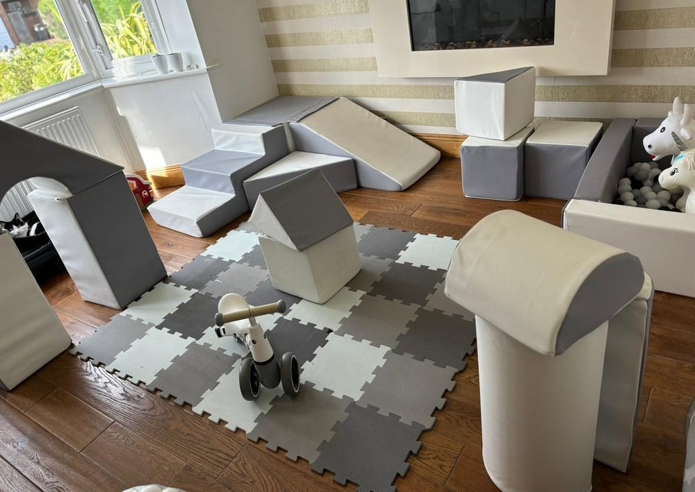 Living room soft play setup with step and slide, soft blocks, ball pit and ride-on unicorn
